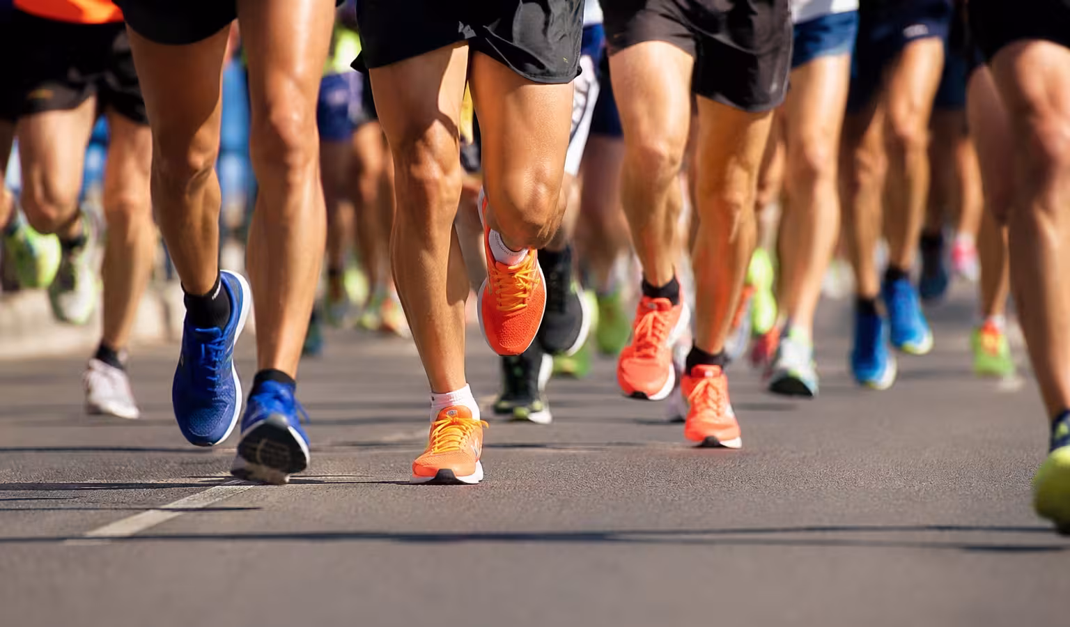 Runners' legs and trainers mid-stride during a road race.